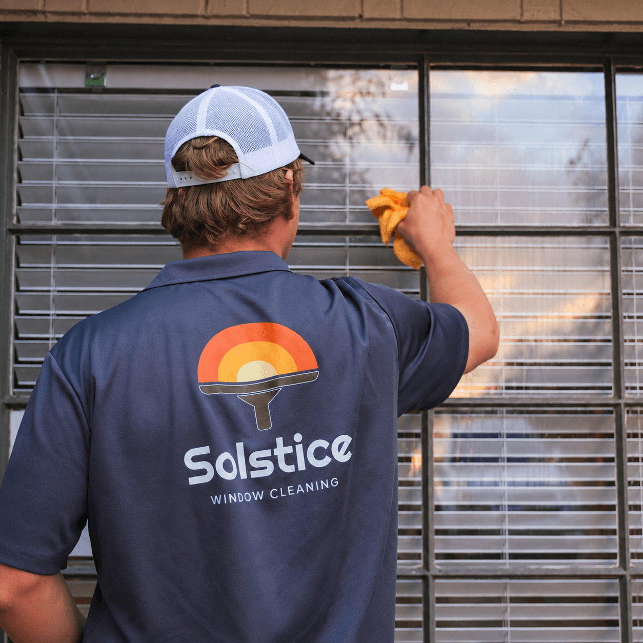 Ben, owner of Solstice Window Cleaning, cleaning a residential window near Scottsdale.