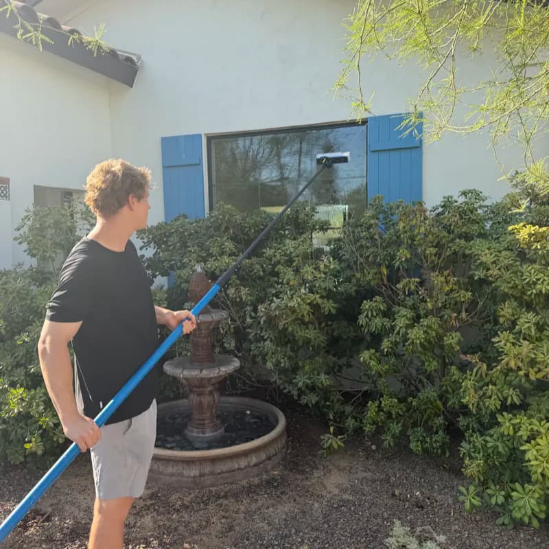 Solstice Window Cleaning owner uses a water-fed pole to clean an exterior home window in Phoenix, Arizona