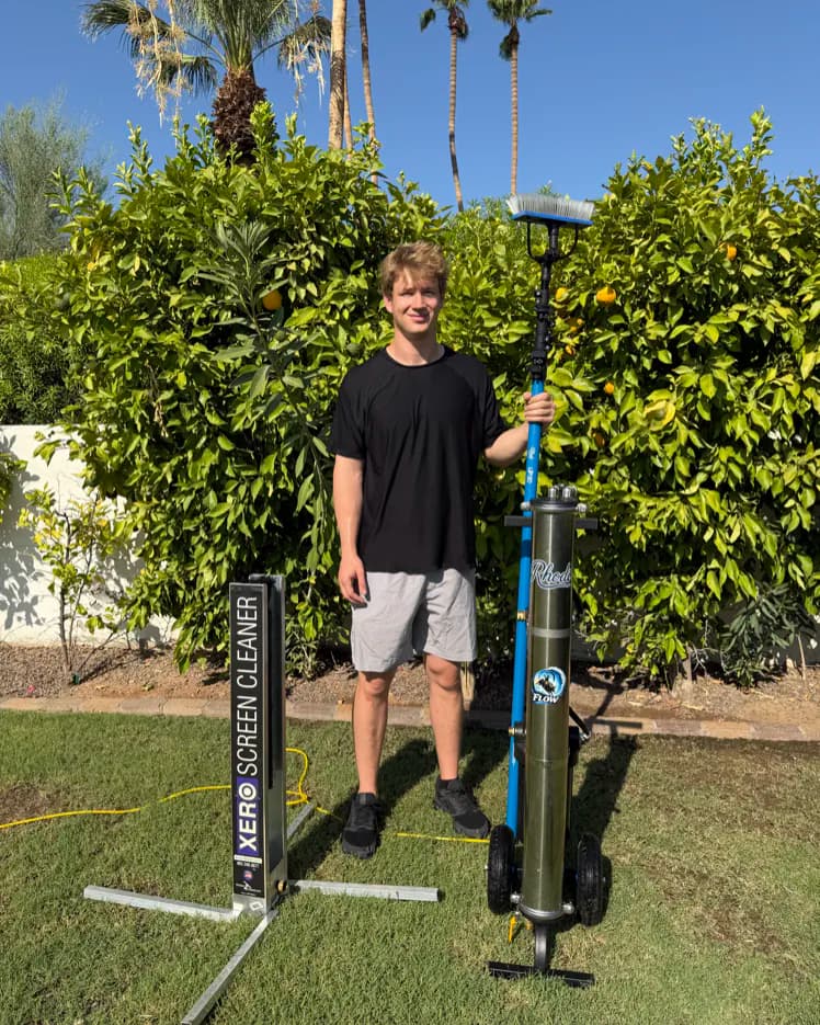 Solstice Window Cleaning owner Ben Hislop with professional window and screen cleaning equipment in a sunny Phoenix yard